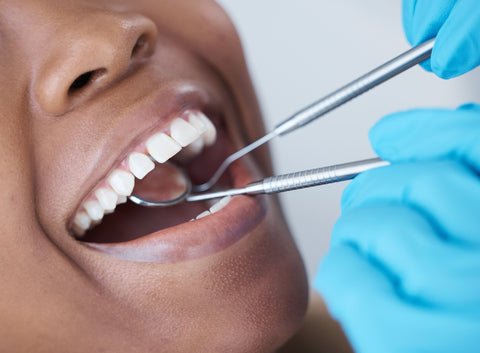 Dentist examining a patient’s smile using a dental mirror during an oral care assessment