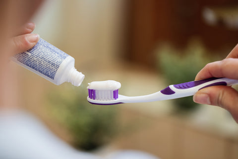 A person squeezing toothpaste onto a toothbrush, preparing for travel-friendly oral care.