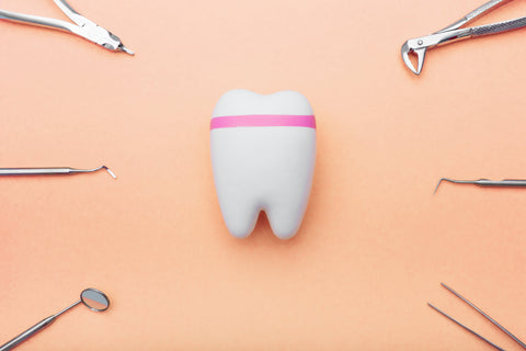 Tooth icon centered on an orange background surrounded by various dental tools, symbolizing comprehensive oral care.